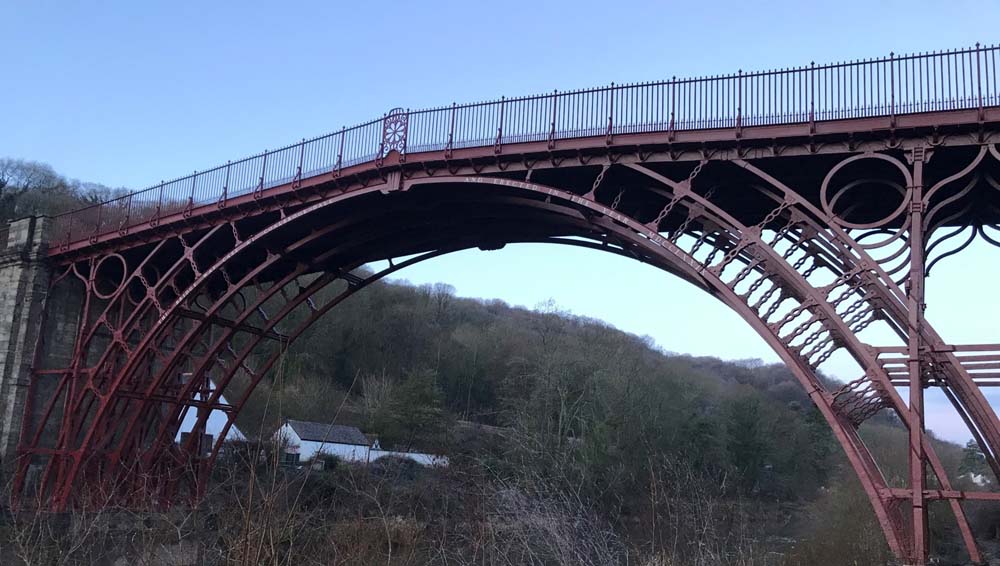 Newly painted red Iron Bridge in front of blue sky.