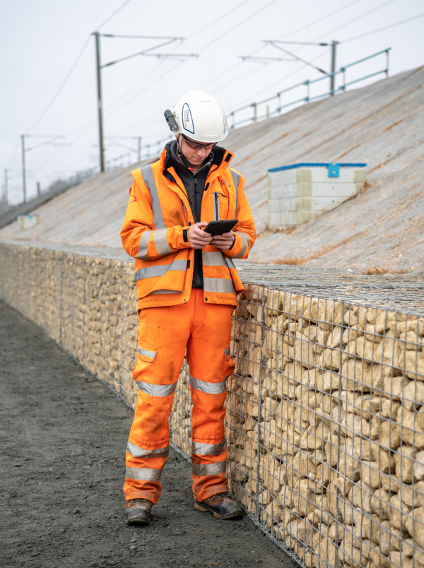 Man in PPE on site using iPad.