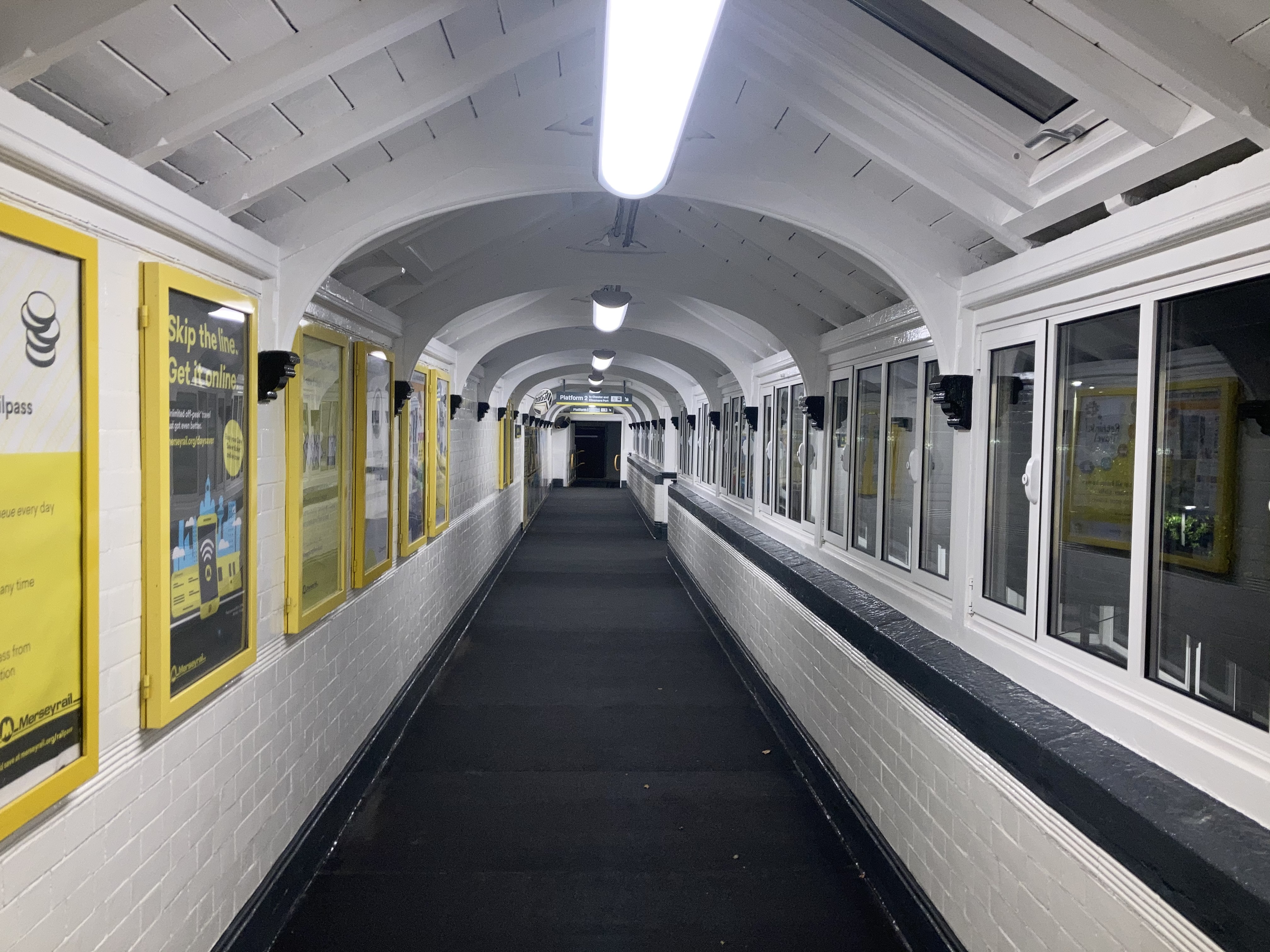 Inside the refurbished Bromborough Station footbridge during the night with new lighting turned on.