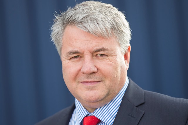 Close up of CEO, Steve Corcoran, with blue background. Headshot.